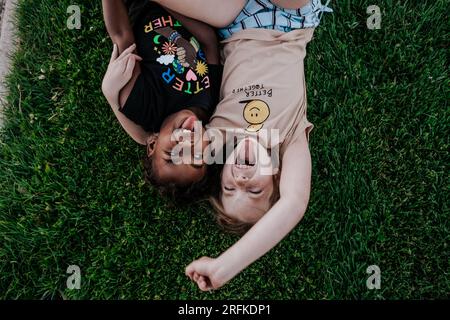 Zwei Mädchen machen alberne Gesichter im Gras Stockfoto