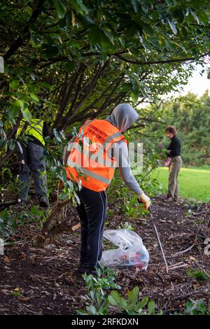 Plastiktüten voller Müll werden vom Community Payback Team vom Gelände eines Sportzentrums entfernt. Stockfoto