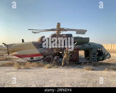 Ein Militärmann steht vor einem abgestürzten Hubschrauber in der Wüste Stockfoto