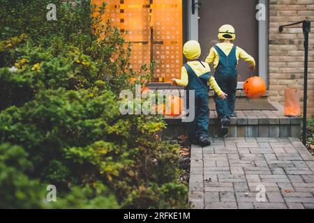 Junge Jungs nähern sich der Haustür, um an Halloween Süßes oder Saures zu spielen. Stockfoto