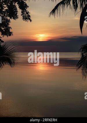 Farbenfroher Sonnenaufgang über dem Karibischen Meer mit Palmensilhouetten Stockfoto