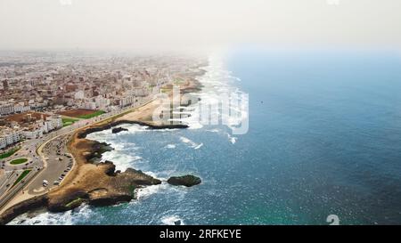 Drohnenansicht von Rabat, Marokko. Felsige Küste des Atlantiks mit Wohngebäuden und Autobahn, Nebel in der Luft Stockfoto