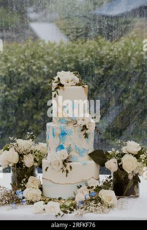 Wunderschöner dreistöckiger Hochzeitstorte mit blauen und goldenen Akzenten Stockfoto