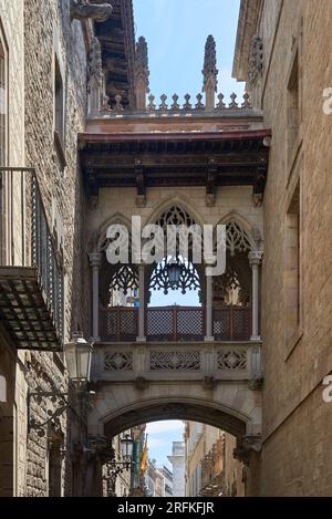 Brücke zwischen Gebäuden im Barri Gotic-Viertel von Barcelona, Spanien. Pont del Bisbe at Dawn - ein Morgenblick auf eine Steinbrücke im neogotischen Stil, Pont Stockfoto