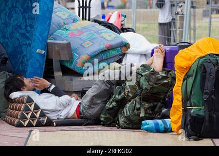 Ein Mann liegt auf dem Boden, umgeben von Betten in einem Lager, das von Demonstranten eingerichtet wurde. Stockfoto