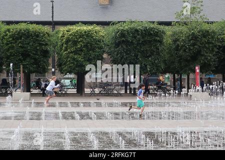 Kleine Kinder laufen gerne durch die tanzenden Springbrunnen und Wasserstrahlen am Granary Square, dem Herzen des neu entwickelten King's Cross in London. Stockfoto