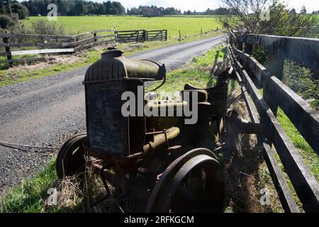 Überreste eines alten Fordson-Traktors neben dem Zaun, Taranaki, North Island, Neuseeland Stockfoto