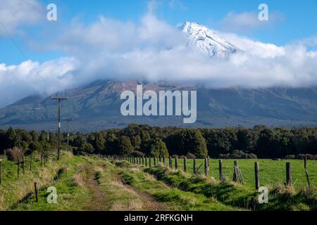 Die unbefestigte Straße führt über das Ackerland in Richtung Mount Taranaki, Nordinsel, Neuseeland Stockfoto