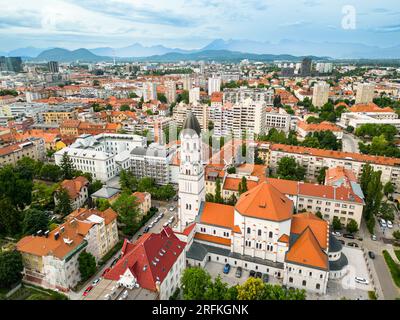 Luftaufnahme von Ljubljana, Slowenien. Historisches Stadtzentrum mit einer Kirche, üppigem Grün und mehreren Wohngebäuden, Hügel auf der Rückseite Stockfoto