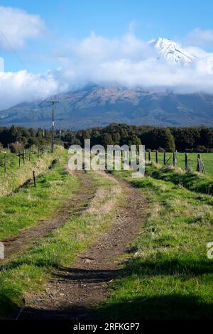 Die unbefestigte Straße führt über das Ackerland in Richtung Mount Taranaki, Nordinsel, Neuseeland Stockfoto