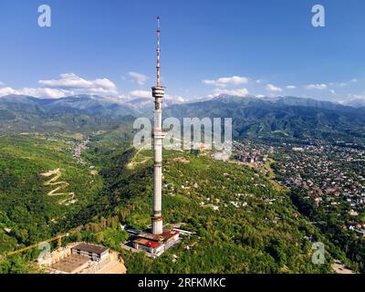 Luftaufnahme der Drohne des Hochfernsehturms von Symbol Almaty City und Park auf dem Koktobe-Hügel vor den Schneebirgen in Kasachstan Stockfoto