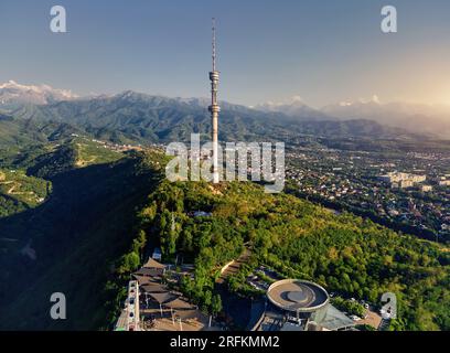 Luftaufnahme der Drohne des Hochfernsehturms von Symbol Almaty City und Park auf dem Koktobe-Hügel vor den Schneebirgen in Kasachstan Stockfoto