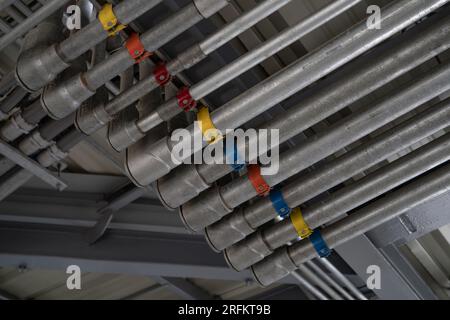 An der Gebäudedecke installiertes Elektrokanalsystem und Elektrokabelrohr Industrielle Infrastruktur. Effiziente elektrische Verdrahtung Stockfoto