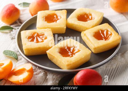 Leckere sommerliche weiche Kekse Cuor di tenerezza mit Aprikosenmarmelade, Nahaufnahme auf einem Teller auf dem Tisch. Horizontal Stockfoto