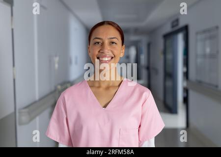 Porträt einer glücklichen, birassischen Ärztin, die im Flur des Krankenhauses Kittel trägt Stockfoto