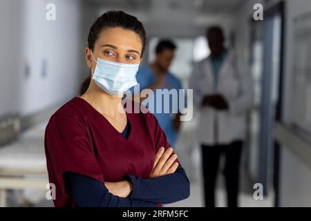 Weiße Ärztin trägt Gesichtsmaske im Flur des Krankenhauses Stockfoto
