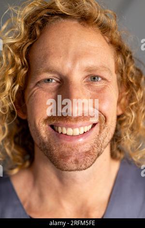 Porträt eines glücklichen weissen Arztes mit lockigem Haar im Korridor des Krankenhauses Stockfoto