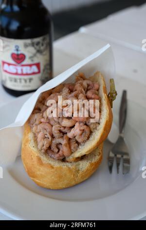 Hamburg, Deutschland - Juni 14 2023: Nordseekrabben-Sandwich oder Nordseekrabben-Brotchen mit einer Flasche Astra Pilsner-Bier. Stockfoto