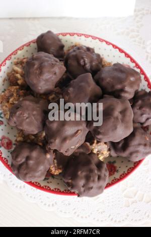 Hausgemachte Süßigkeiten aus Nüssen und getrockneten Früchten. Einige sind mit Schokolade bedeckt. Sie liegen auf einem Teller. Stockfoto