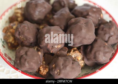 Hausgemachte Süßigkeiten aus Nüssen und getrockneten Früchten. Einige sind mit Schokolade bedeckt. Sie liegen auf einem Teller. Stockfoto