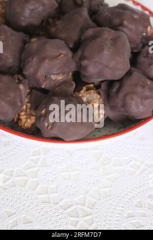 Hausgemachte Süßigkeiten aus Nüssen und getrockneten Früchten. Einige sind mit Schokolade bedeckt. Sie liegen auf einem Teller. Stockfoto