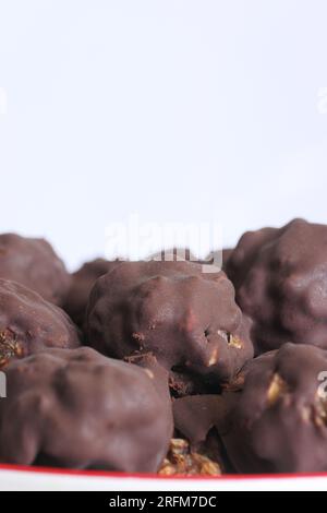 Hausgemachte Süßigkeiten aus Nüssen und getrockneten Früchten. Einige sind mit Schokolade bedeckt. Sie liegen auf einem Teller. Nahaufnahme. Stockfoto