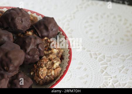 Hausgemachte Süßigkeiten aus Nüssen und getrockneten Früchten. Einige sind mit Schokolade bedeckt. Sie liegen auf einem Teller. Stockfoto