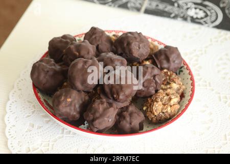 Hausgemachte Süßigkeiten aus Nüssen und getrockneten Früchten. Einige sind mit Schokolade bedeckt. Sie liegen auf einem Teller. Stockfoto