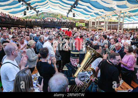 Herne, Deutschland. 04. August 2023. Die Bergmannsorchester (Band der Kohlebergarbeiter) kommt. Der Premierminister von Nordrhein-Westfalen, Hendrik Wüst (CDU), kommt zusammen mit Bürgermeister Frank Dudda (SPD) und anderen Würdenträgern, um die Menge und die Darbietungen anzufeuern, und klopft dann das Fass im festlichen Zelt an, um das Cranger Kirmes-Messegelände in Herne offiziell zu eröffnen. Die Cranger Kirmes ist eine der größten in Deutschland. Popsängerin Michelle und andere treten auf. Die beliebte Messe zieht während ihres 10-tägigen Laufs regelmäßig mehr als 4m Besucher an. Die Messe stammt aus dem frühen 18. Jahrhundert in Crange. Stockfoto