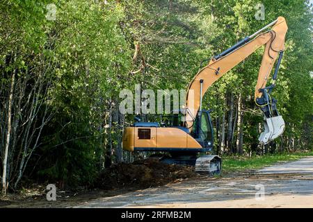 Raupenbagger vertieft den Sturmgraben auf Landstraßen. Stockfoto