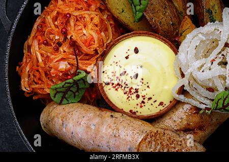 Gebratene Würstchen mit gebackenen Kartoffeln, gedünsteter Kohl, in einer Pfanne. Nahaufnahme Stockfoto