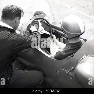 1962, historisch, in der Geoff Clarke Rennfahrerschule am Finmere Aerodrome, Bucks, England, Großbritannien, ein Lehrer, der einem jungen Fahrer in einem Cooper Einsitzer-Rennwagen alles erklärt. Stockfoto