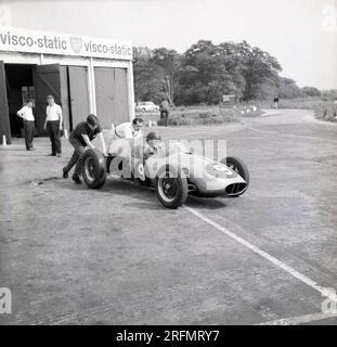 1962, historisch, ein junger männlicher Fahrer sitzt in einem einsitzigen Cooper-Rennwagen und wird auf die Rennstrecke geschoben in der Rennfahrerschule des Finmere Aerodrome, Bucks, England, Großbritannien, Stockfoto