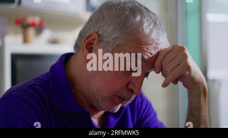 Ein hoffnungsloser Senior-Mann, der allein zu Hause mit Depressionen zu kämpfen hat. Nahgesicht eines älteren Menschen in stiller Verzweiflung, melancholischer und psychischer Erkrankung dargestellt Stockfoto