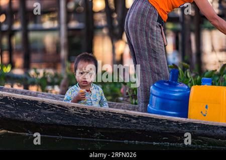 Ein Kleinkind mit burmesischer Thanaka-Sonnencreme auf einem traditionellen Holzboot in Inle Lake, Myanmar, Asien Stockfoto