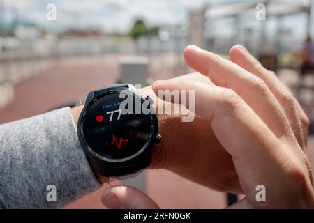 Nahaufnahme des Smart Watch Health Tracker mit der auf dem Bildschirm angezeigten Herzfrequenz. Modernes, elegantes und innovatives tragbares Gerät. Sportler überprüft sein Hörvermögen Stockfoto