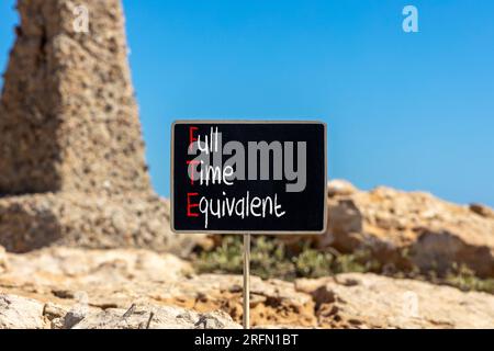 FTE-Symbol für Vollzeitäquivalent. Konzeptwörter FTE Vollzeitäquivalent auf wunderschöner schwarzer Kreidetafel. Wunderschöner Steinstrand im Hintergrund. Geschäfte Stockfoto