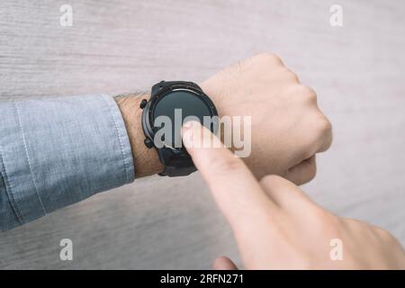 Fitnessuhr am mans-Unterarm mit Datum, Uhrzeit, Herzfrequenz und Schrittzähler. Stockfoto