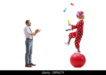 Profilaufnahme über die gesamte Länge eines Mannes, der mit Händen klatscht und einem Clown zusieht, der mit Bällen jongliert, isoliert auf weißem Hintergrund Stockfoto