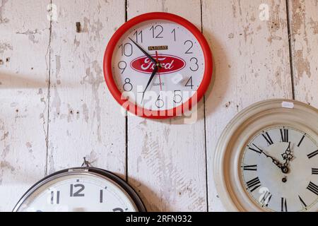 Schilder und Symbole, ein Flohmarkt, eine Wanduhr mit einem Ford-Emblem. Stockfoto