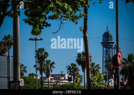 Barcelona, Spanien - Mai 26 2022: Zwei rote Kutschen fahren mit der Seilbahn und passieren den Turm in Barcelona. Eine der Touristenattraktionen. Stockfoto