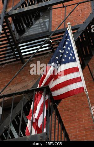 Eine amerikanische Flagge mit Sternen und Streifen hängt über der Feuertreppe in New York City. Stockfoto