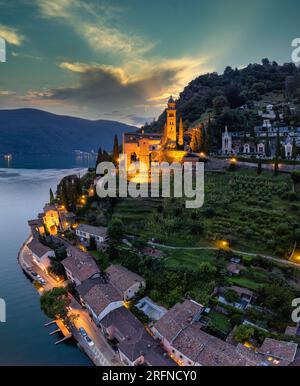 Luftbild der Pfarrkirche Madonna del Sasso steht auf dem hohen Hügel von Vico Morcote bei Sonnenuntergang. Morcote am Luganer See wurde einst als Stockfoto