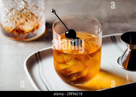 Alkoholisches Manhattan Drink on the Rocks Bourbon Whiskey und garnieren mit Maraschino Kirschen Stockfoto