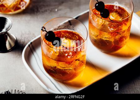 Alkoholisches Manhattan Drink on the Rocks Bourbon Whiskey und garnieren mit Maraschino Kirschen Stockfoto