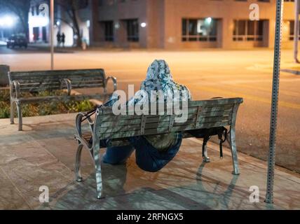 Ein Mann, der auf der Straße lebt, versucht, sich in der Innenstadt von Austin an einem kühlen Januarabend im Zentrum von Texas warm zu halten. ©Bob Daemmrich Stockfoto