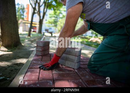 Im Sommer werden Straßenbauarbeiten zum Verlegen eines neuen Fußgängerwegs durchgeführt. Stockfoto