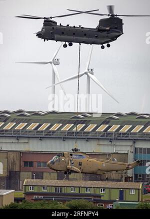 RAF Chinook vom 28. Geschwader RAF Benson Last hebt einen Ex Royal Navy Seaking Helicopter auf RAF St Mawgan Stockfoto