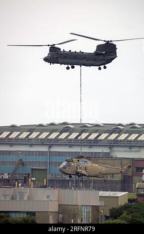 RAF Chinook vom 28. Geschwader RAF Benson Last hebt einen Ex Royal Navy Seaking Helicopter auf RAF St Mawgan Stockfoto