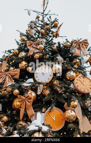 Weihnachtsuhr und goldene Einrichtung am Weihnachtsbaum. Magische Details zum neuen Jahr. Vertikale festliche Tapete Stockfoto